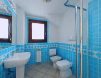 a glass with a blue tiled shower and sink